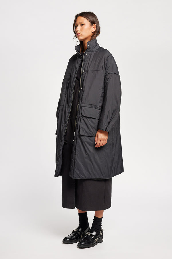 Font angle view on model of the oversized Restore Coat in Black, showcasing  relaxed silhouette and clean lines