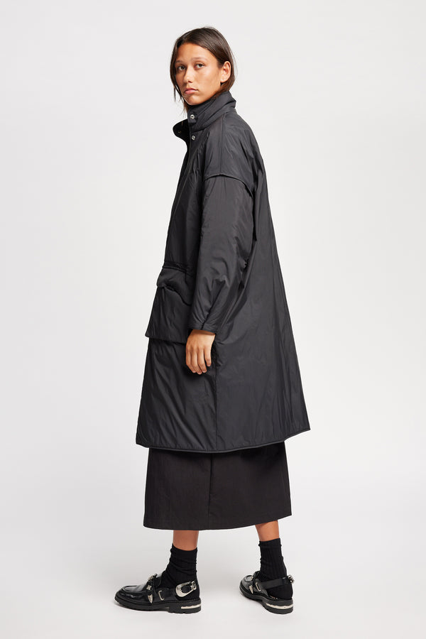 Side view on model of the oversized Restore Coat in Black, showcasing  relaxed silhouette and clean lines