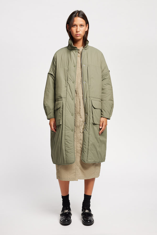 Font view on model of the oversized Restore Coat in Dusty Olive Green, showcasing  relaxed silhouette and clean lines