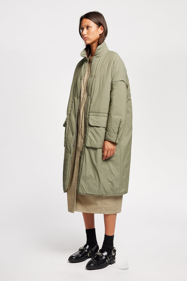 Font angle view on model of the oversized Restore Coat in Dusty Olive Green, showcasing  relaxed silhouette and clean lines