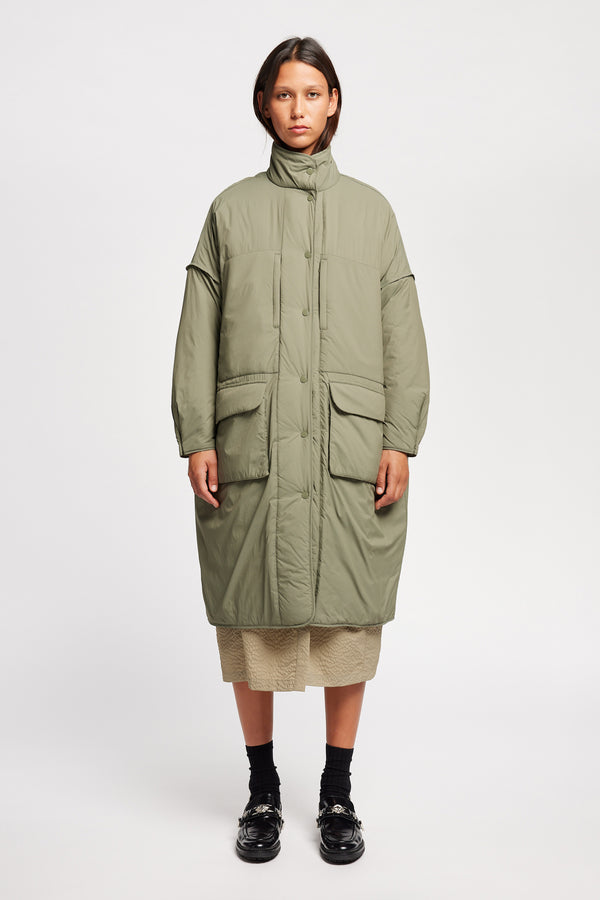 Font view on model of the oversized Restore Coat in Dusty Olive Green, showcasing  relaxed silhouette and clean lines