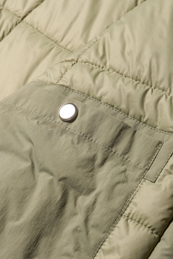 Close-up of zip stud button closure on inside pocket and quilted texture on the Restore Coat in Dusty Olive green
