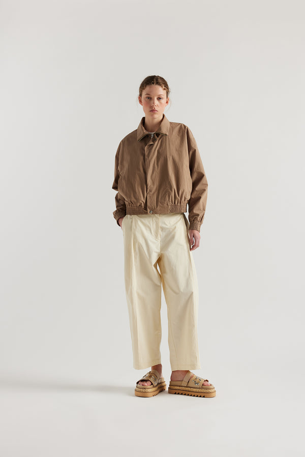 Front view of model in the fawn brown Reverie Jacket showing two-way zip closure and topstitched welt pockets.