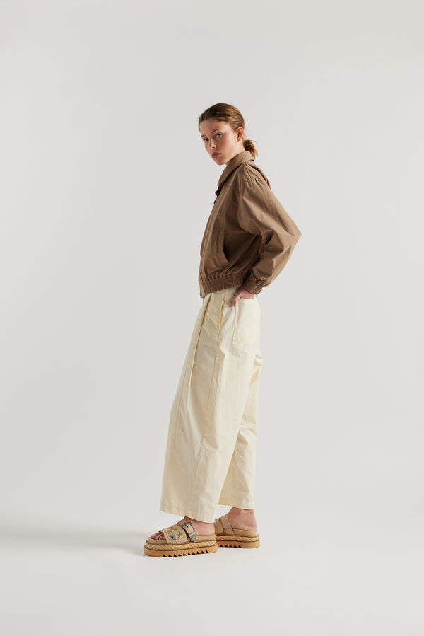 Side view of model in the fawn brown Reverie Jacket showing two-way zip closure and topstitched welt pockets.
