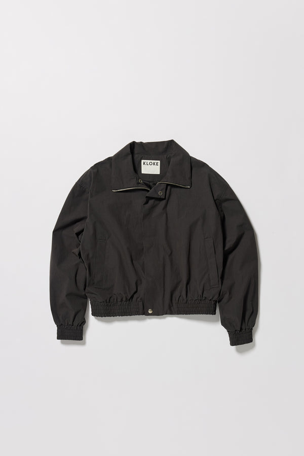 Flat Front of the black slate Reverie Jacket showing two-way zip closure and topstitched welt pockets.