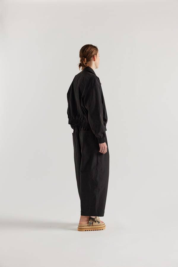 Back view of model in the black slate Reverie Jacket showing two-way zip closure and topstitched welt pockets.
