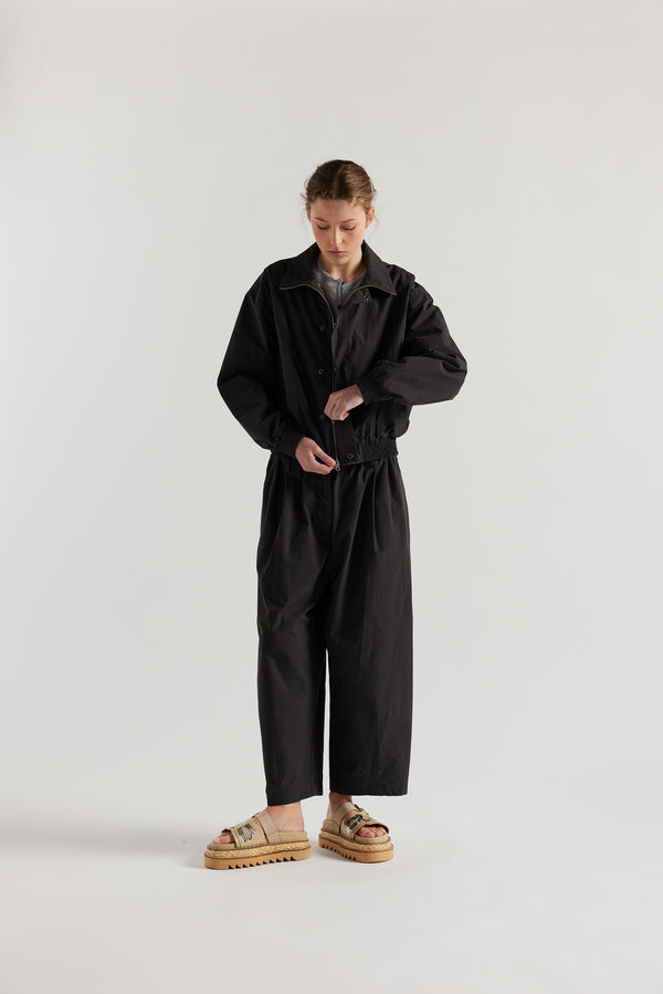 Front view of model in the black slate Reverie Jacket showing two-way zip closure and topstitched welt pockets.