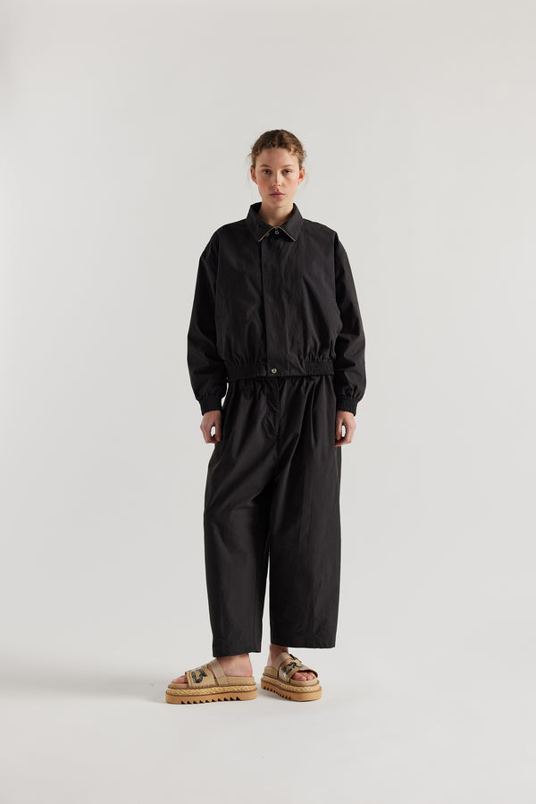 Front view of model in the black slate Reverie Jacket showing two-way zip closure and topstitched welt pockets.