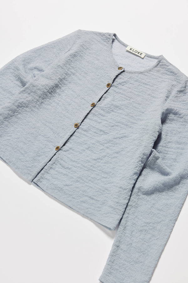 Close-up of Rising LS Shirt in Pale Blue showing rounded self-bind collar and subtle textured lightweight fabric.
