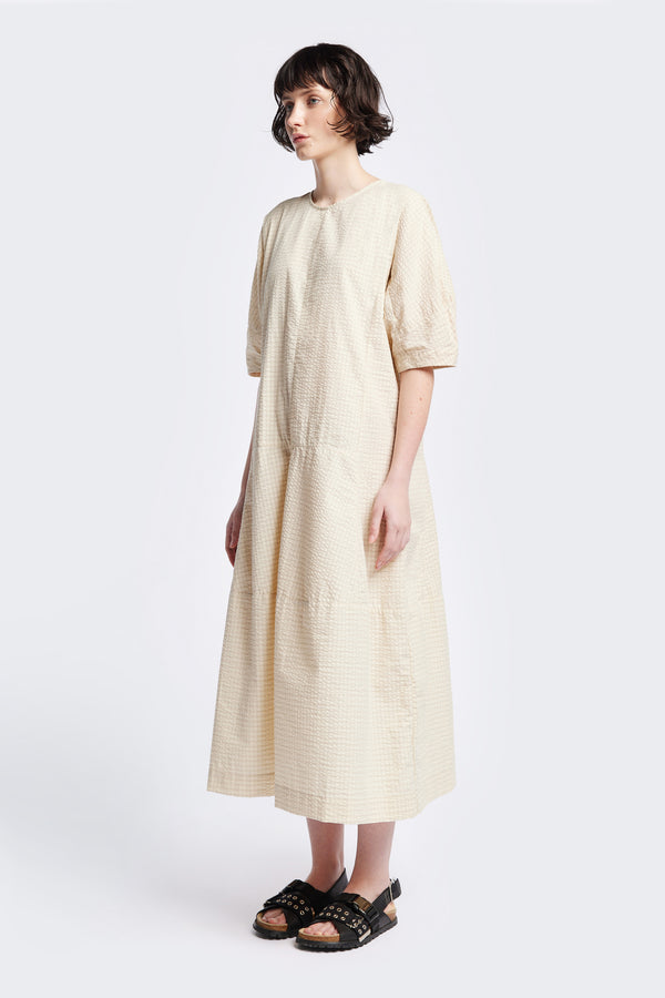 The Scoria Dress in Ecru beige, a long-panelled cotton seersucker dress with voluminous sleeves, structured panel details, and a fuller skirt, perfect for an effortless summer look. Available in 5 sizes. 