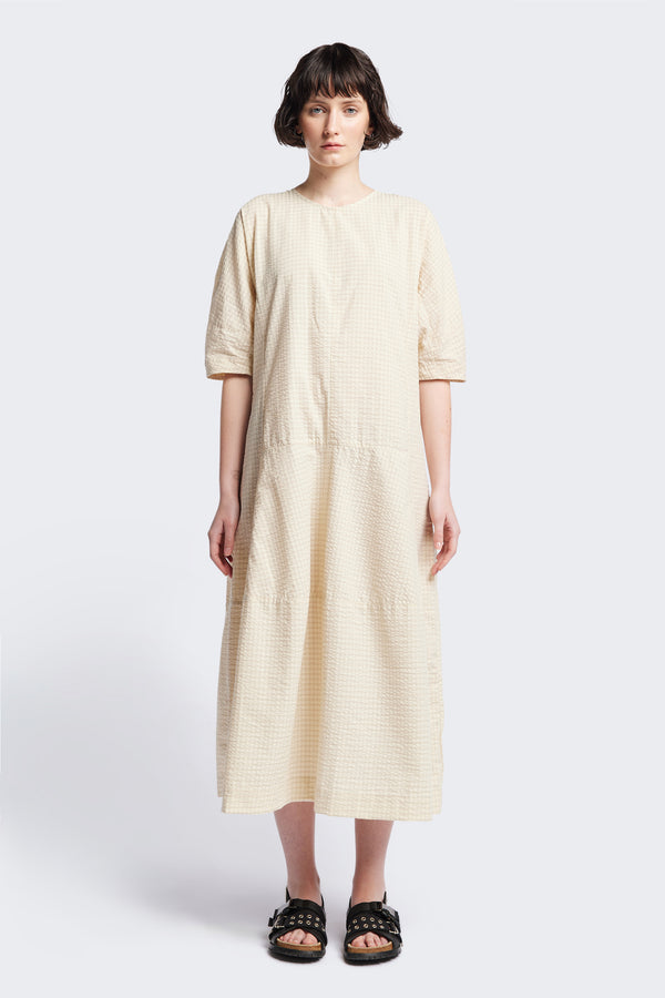 The Scoria Dress in Ecru beige, a long-panelled cotton seersucker dress with voluminous sleeves, structured panel details, and a fuller skirt, perfect for an effortless summer look. Available in 5 sizes. 