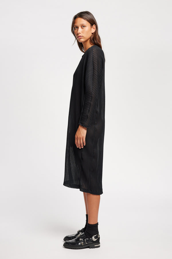 Side view of black Sequel Dress with high neckline, midi length, and bracelet sleeves