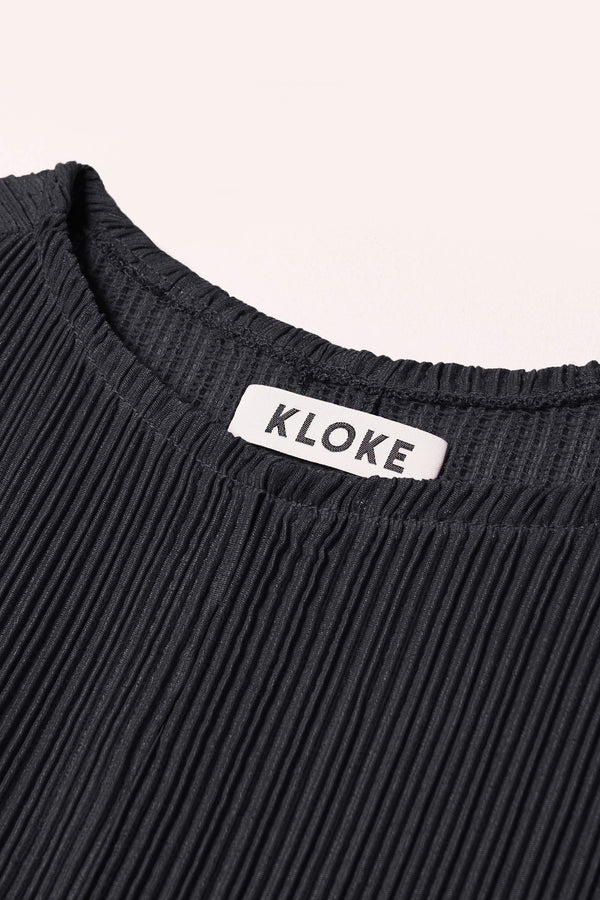 Close up fabric detail of the black Sequel Dress with high neckline, midi length, and bracelet sleeves