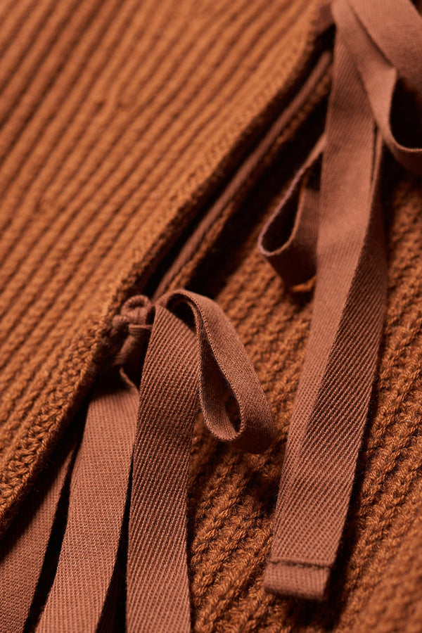 Close up fabric detail shot of toffee brown sleeveless ribbed knit vest with side ties in merino and cotton blend