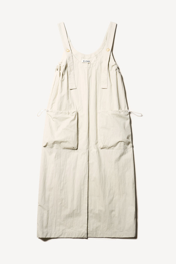 Flat Font of the Shoreline full-length pinafore dress in bone white with deep round neckline and front patch pockets, a relaxed-fit silhouette. 