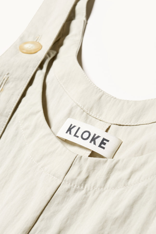 Close up details shot of the Shoreline full-length pinafore dress in bone white. Focussing on fabric and adjustable arm strap detail. 