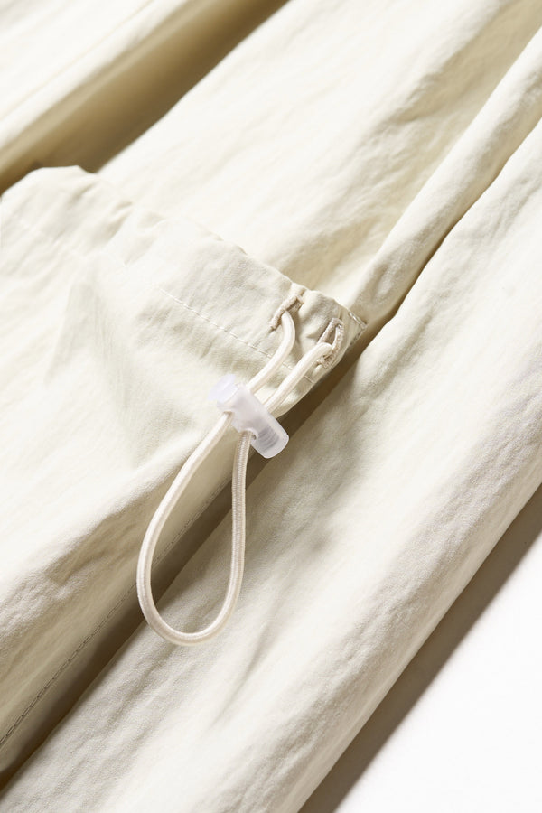 Close up details shot of the Shoreline full-length pinafore dress in bone white. Focussing on fabric and adjustable pocket. 