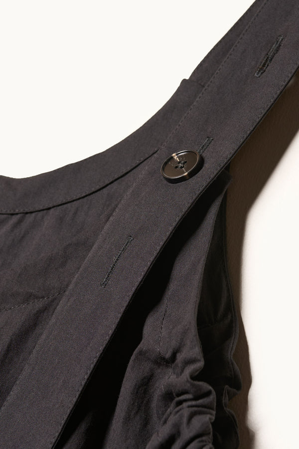 Close up details shot of the Shoreline full-length pinafore dress in black. Focussing on fabric and adjustable arm strap detail. 