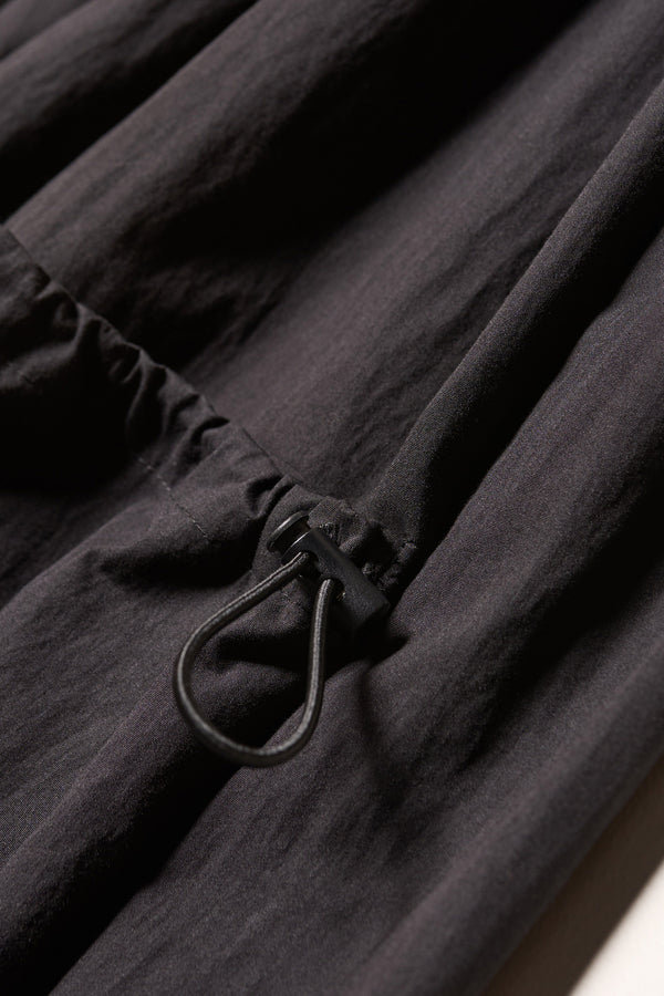 Close up details shot of the Shoreline full-length pinafore dress in black. Focussing on fabric and adjustable pocket. 