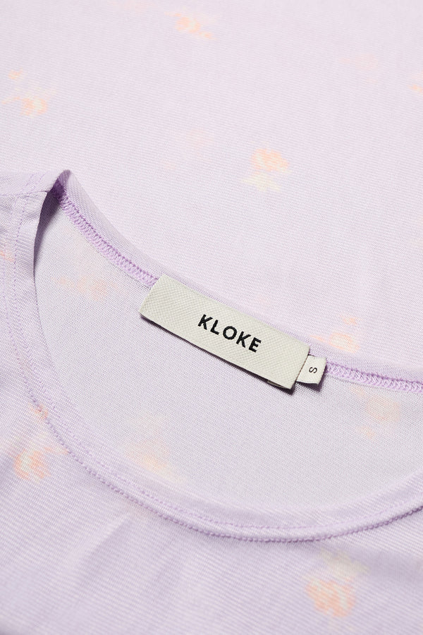 Close up fabric shot of the Spring Mesh Long Sleeve Top in lilac floral, featuring a delicate floral print on lightweight, sheer mesh fabric. Ideal for layering under dresses or shirts. Available in 6 sizes. 