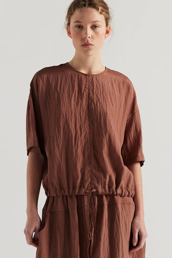 Front of model in the cocoa brown Stillness Top with round neckline and centre front seam detail.