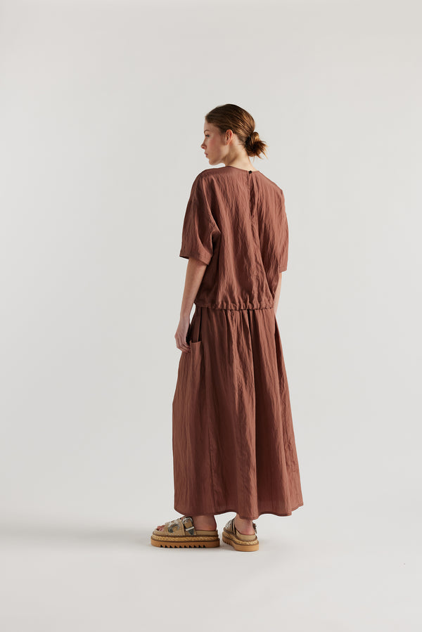 Back of model in the cocoa brown Stillness Top with round neckline and centre front seam detail.