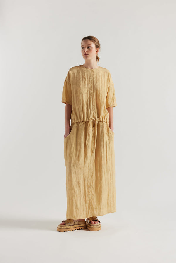 Front of model in the sand beige Stillness Top with round neckline and centre front seam detail.