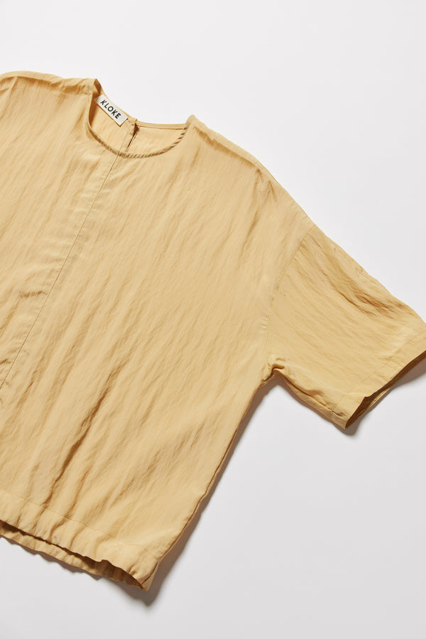 Detail shot of the sand beige Stillness Top showcasing the fabric texture and round neckline