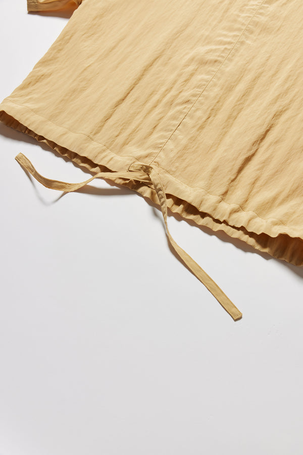 Detail shot of the sand beige Stillness Top showcasing the self-encased hem tie on the Stillness Top.