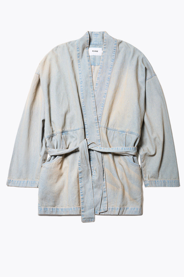 Flat Front of the unisex Subterra Wide wrap shawl collar jacket with kimono-style sleeves, crafted from cotton denim, featuring front patch pockets and a waist tie to cinch the loose silhouette. Available in 5 sizes.  