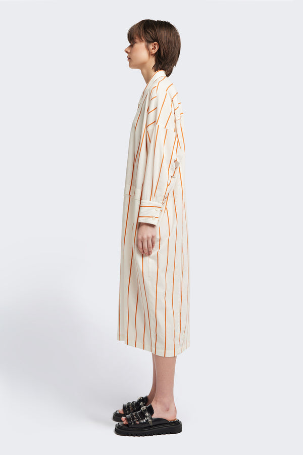 Side view of the Sundown Shirt Dress in Burnt Orange Stripe, a relaxed-fit, knee-length shirt dress with a cocooned back and front tuck detail.