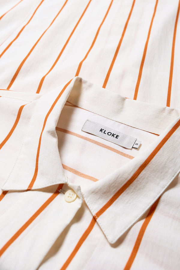 Close up fabric details of the Sundown Shirt Dress in Burnt Orange Stripe, a relaxed-fit, knee-length shirt dress with a cocooned back and front tuck detail.