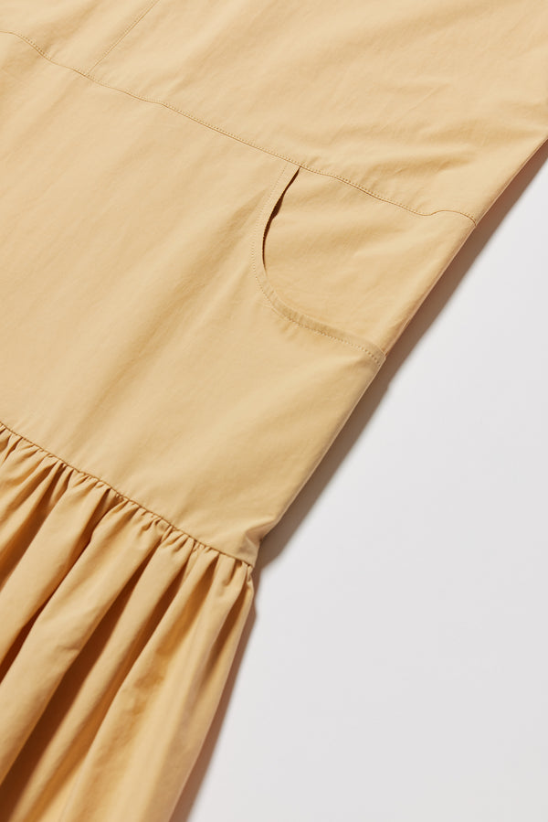 Detail shot off the Surrender Dress in sand showing panelled detailing, dropped waist, and gathered skirt. 