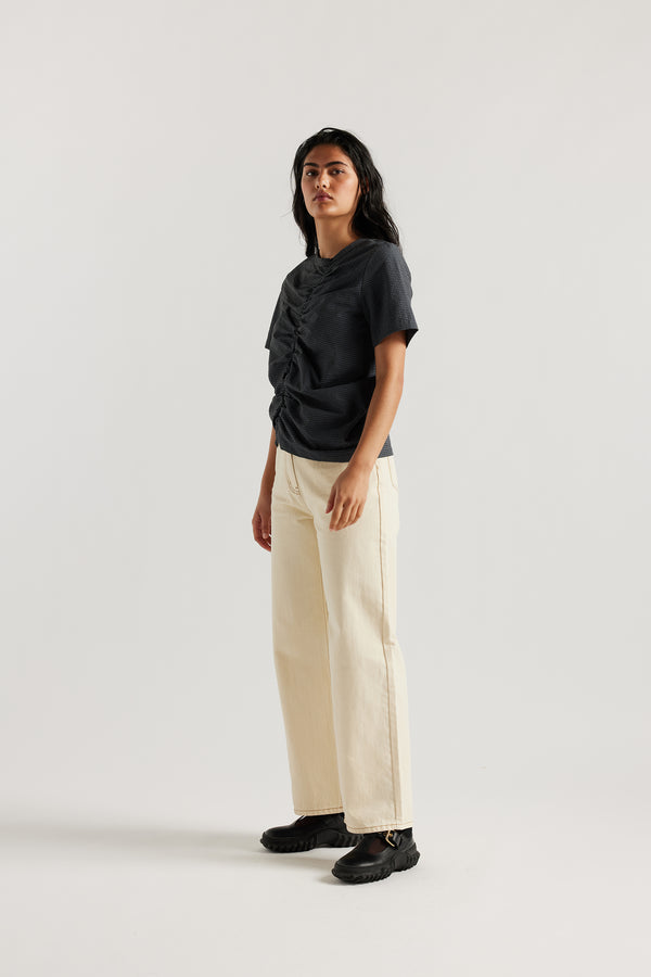 Model wearing relaxed straight-leg ecru jeans in a timeless vintage wash with high to mid rise and slim hip fit