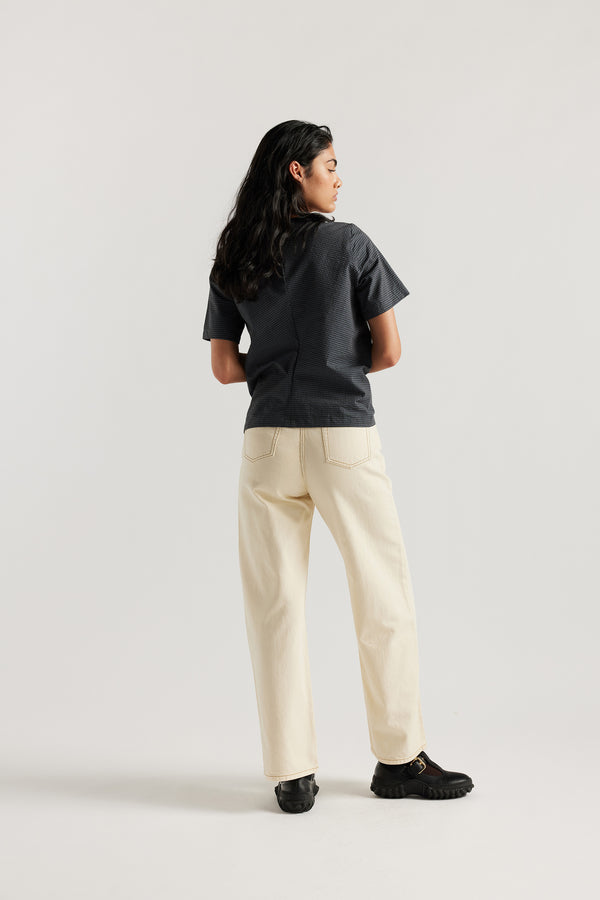 Model wearing relaxed straight-leg ecru jeans in a timeless vintage wash with high to mid rise and slim hip fit