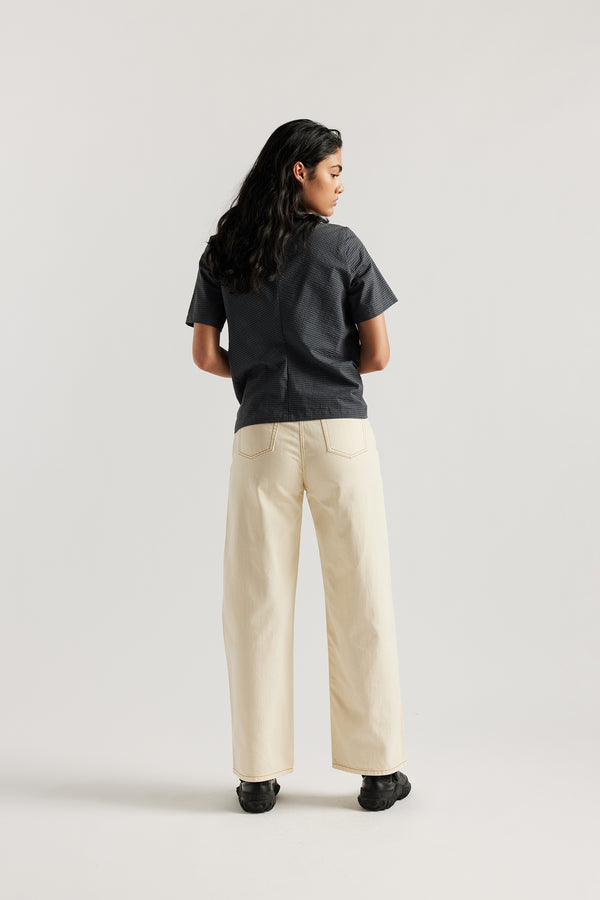 Model wearing relaxed straight-leg ecru jeans in a timeless vintage wash with high to mid rise and slim hip fit