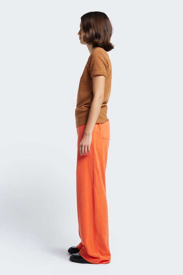 Side profile of the Prone Towelling Track Pant, a straight leg, slouchy track pant crafted from Okeo-tex standard cotton terry in Tangerine Orange.