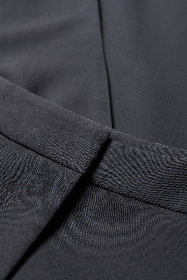 Close up fabric details of the Tranquillity Pant in black, a slim-fit stovepipe-style tailored pant with pin tuck detailing.