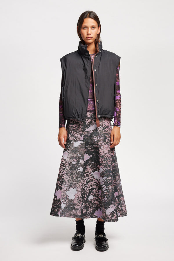 Front view of Model wearing the Transform Puffa Jacket in black with sleeves removed, sip undone, showcasing cropped length and high collar