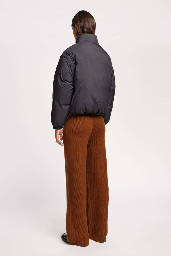 Back of the Model wearing the Transform Puffa Jacket in black with sleeves attached, zipped up, showcasing cropped length and high collar