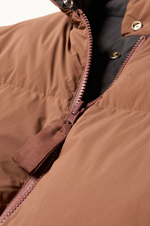Close-up detail shot of zip detail and stud button closure on Transform Puffa Jacket in Black and Toffee Brown
