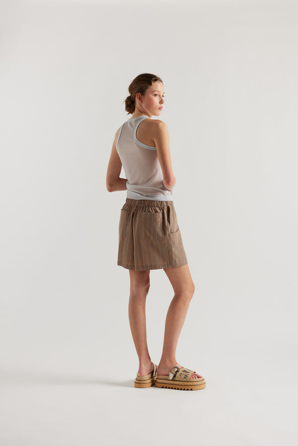 Back view on female model of the Pale Blue Transformation Tank in sheer fabric with racerback neckline.