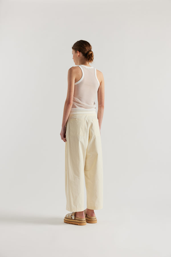 Back view on female model of the White Transformation Tank in sheer fabric with racerback neckline.