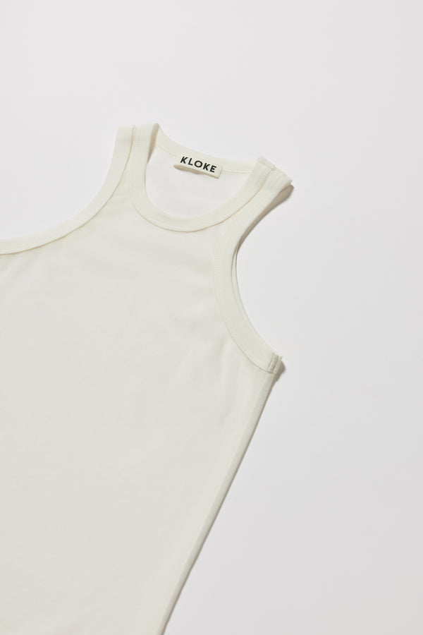 Detail of ribbed binding at neckline and armholes of the white Transformation Tank in sheer fabric with racerback neckline.