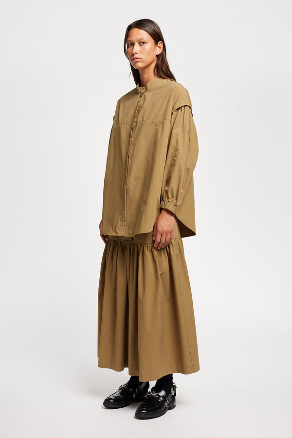 Front Angle view of the Model wearing the Transit Gathered Blouse in Dusty Olive a relaxed band collar shirt with dropped shoulders, pleated sleeves, and a curved hemline.