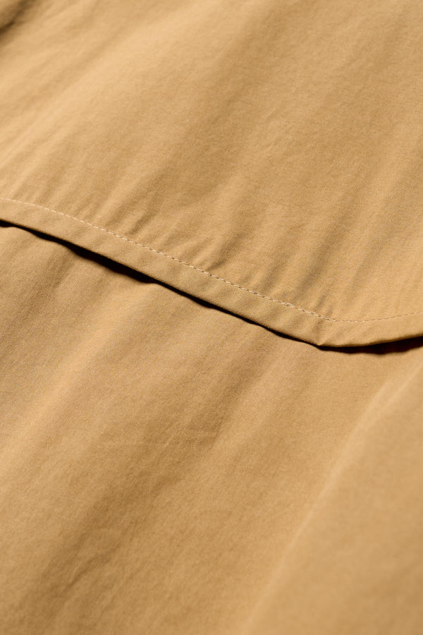 Close up fabric details of the Transit Gathered Blouse in Dusty Olive a relaxed band collar shirt with dropped shoulders, pleated sleeves, and a curved hemline.