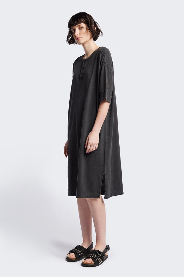 The Treatise Henley Dress in Black soft jersey, featuring a relaxed boxy fit, crew neckline, henley button detail, and falling just below the knee. Available in 5 sizes.