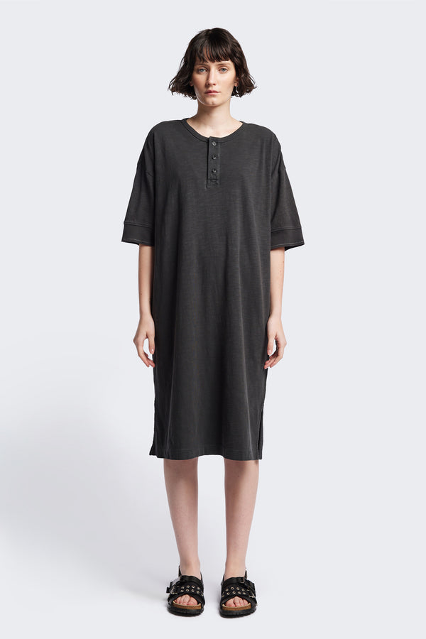 The Treatise Henley Dress in Black soft jersey, featuring a relaxed boxy fit, crew neckline, henley button detail, and falling just below the knee. Available in 5 sizes.