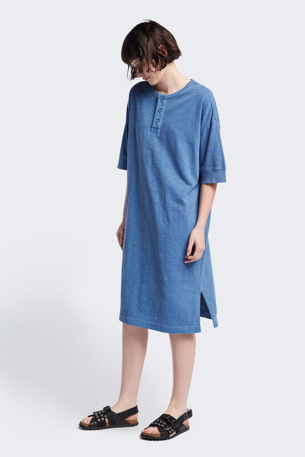 The Treatise Henley Dress in Blue soft jersey, featuring a relaxed boxy fit, crew neckline, henley button detail, and falling just below the knee. Available in 5 sizes.