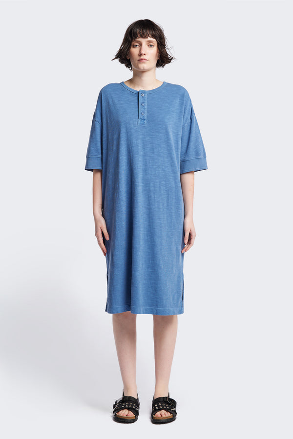 The Treatise Henley Dress in Blue soft jersey, featuring a relaxed boxy fit, crew neckline, henley button detail, and falling just below the knee. Available in 5 sizes.